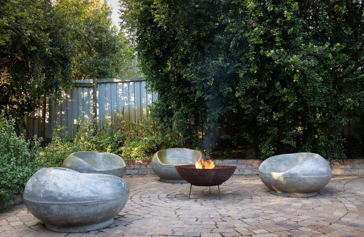 Paver courtyard with a round fire bowl and curved stone seats